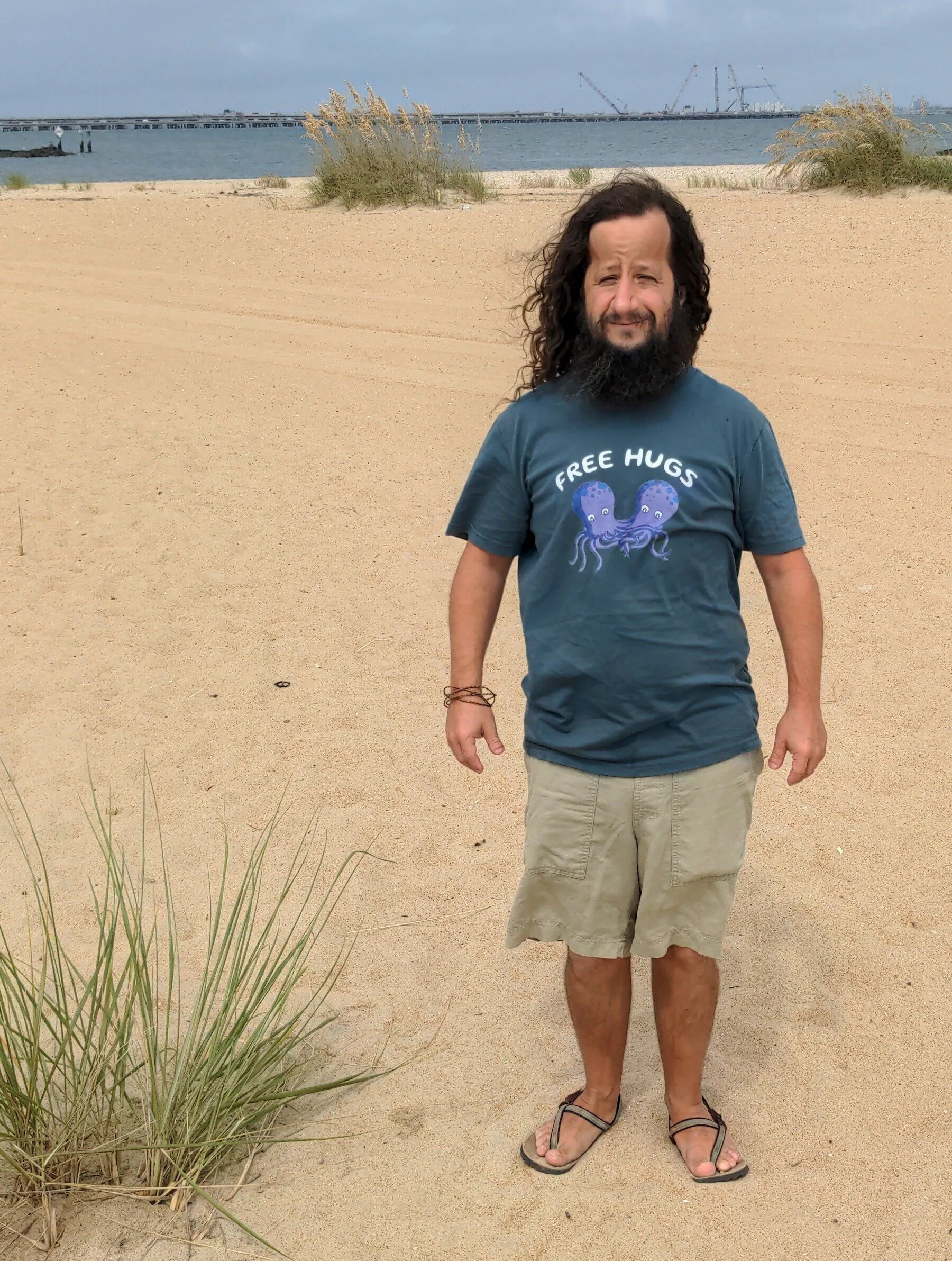 David Barbarisi standing on a beach wearing a grey 'Free Hugs' t-shirt with an octopus graphic